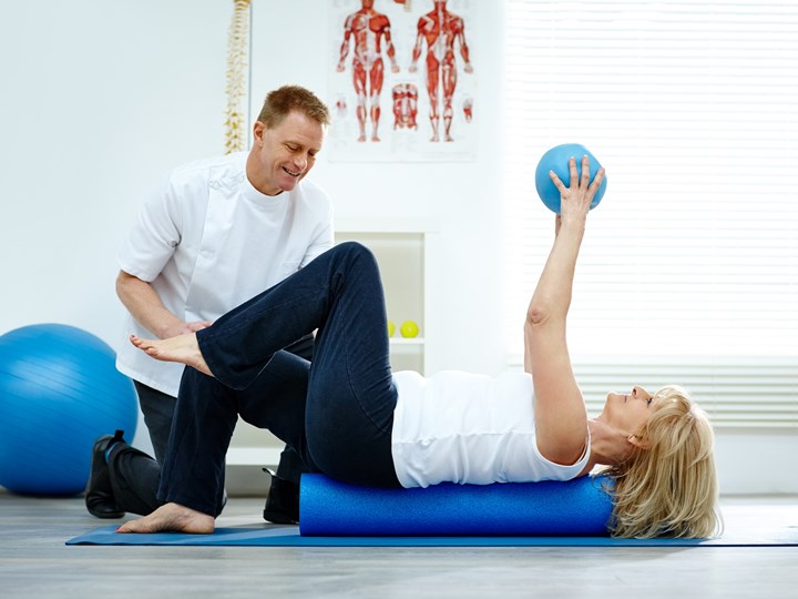 Patientin macht Übungen mit Physiotherapeut